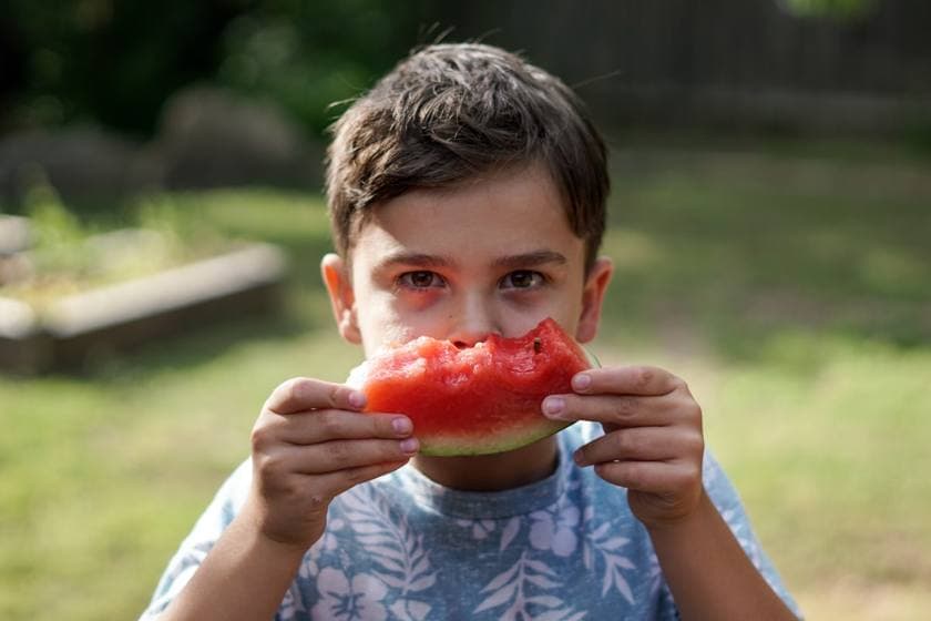 A happy child eating fresh fruit