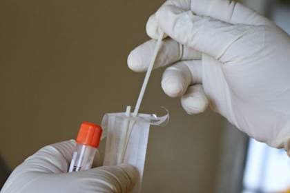 A swab being placed into a sample tube